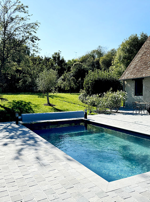 Piscine chauffée avec accès direct depuis la cuisine, ouvrant sur une terrasse pavée idéale pour les repas d’été et les soirées en plein air.